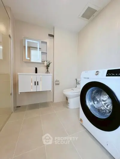 Modern bathroom with washing machine and sleek vanity in a contemporary home.