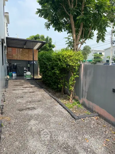 Charming backyard with gravel path and lush greenery, perfect for outdoor relaxation and gardening.