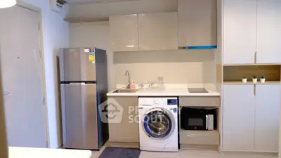 Modern kitchen with sleek appliances including fridge, washing machine, and microwave in a compact layout.