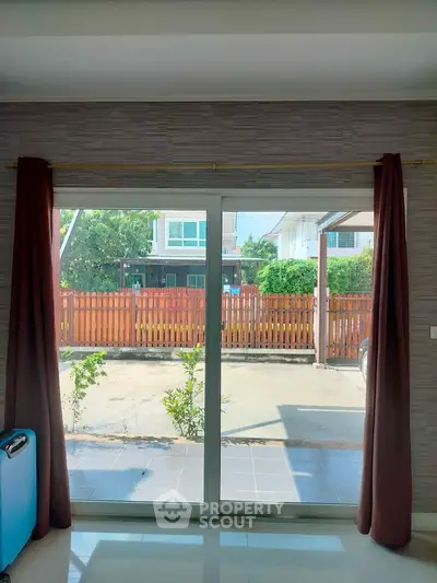 Spacious living room with sliding glass doors opening to a sunny patio and garden view.