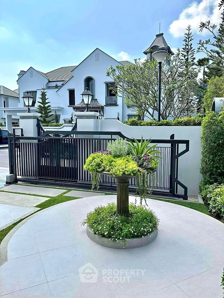 Elegant white villa with lush garden and modern gate in a serene neighborhood.
