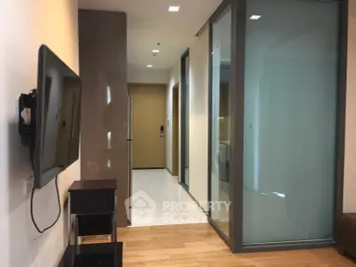 Modern apartment hallway with sleek design and wall-mounted TV, showcasing contemporary living.