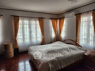 Spacious bedroom with natural light and elegant curtains