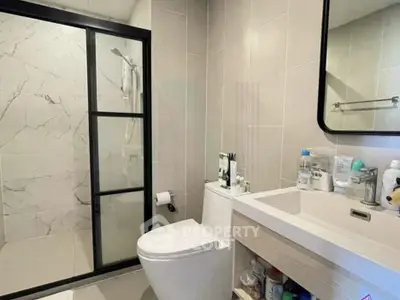 Modern bathroom with glass shower and sleek vanity in contemporary home.