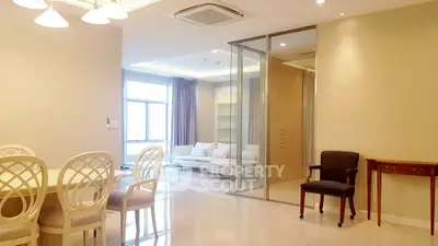 Spacious modern living room with elegant dining area and glass partition, featuring natural light and stylish decor.