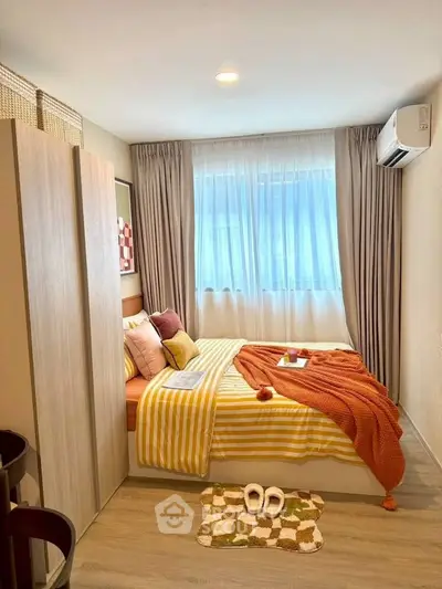 Cozy bedroom with modern decor, featuring a comfortable bed, stylish wardrobe, and natural light from large window.