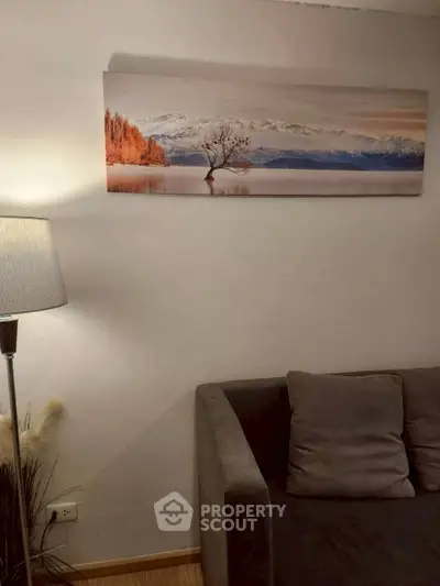 Cozy living room with modern decor and elegant wall art, featuring a comfortable gray sofa and stylish floor lamp.