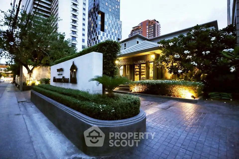 Luxurious modern building entrance with lush landscaping and ambient lighting