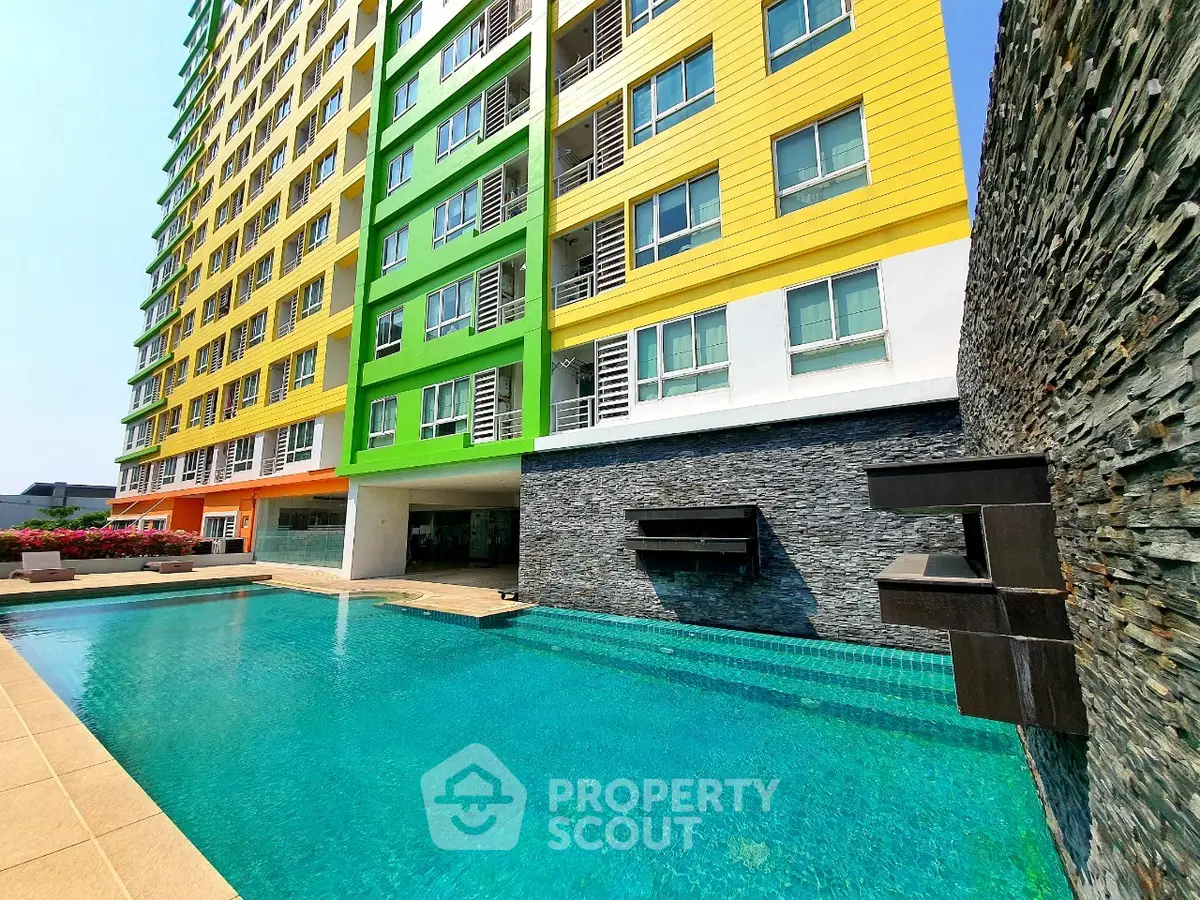 Modern apartment building with vibrant colors and luxurious pool area.