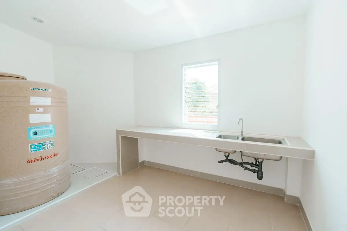 Spacious utility room with large water tank and sink, ideal for storage and laundry.