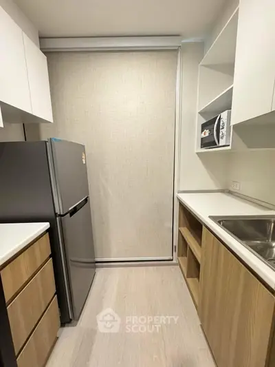 Modern kitchen with sleek cabinetry and stainless steel fridge in compact layout.