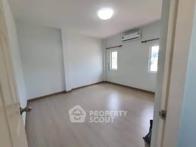 Spacious empty bedroom with wooden flooring and air conditioning, perfect for customization.