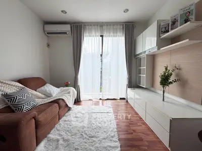 Cozy living room with modern decor, plush sofa, and natural light through large windows.