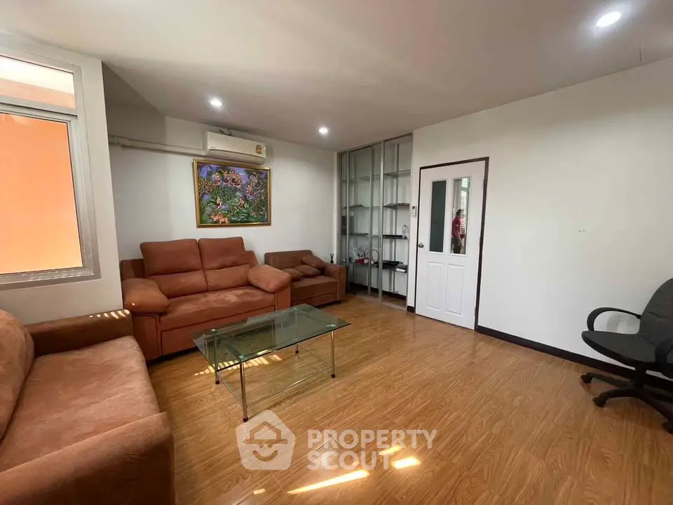 Spacious living room with modern furniture and wooden flooring, perfect for relaxation and entertainment.