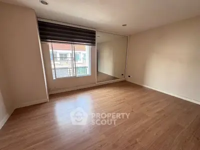 Spacious empty room with large window and mirrored wall, perfect for customization.