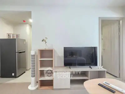 Modern living room with sleek furniture and flat-screen TV, adjacent to a compact kitchen area.