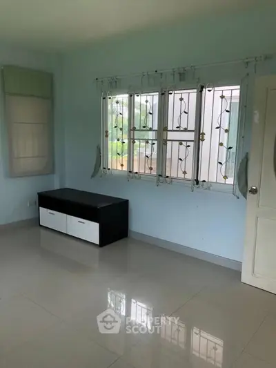 Spacious room with large window and modern storage unit, perfect for versatile living space.