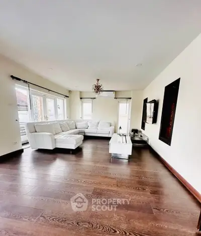 Spacious living room with elegant hardwood floors and modern white sectional sofa.