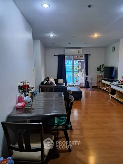 Spacious living room with modern decor and wooden flooring, featuring a cozy seating area and dining space.
