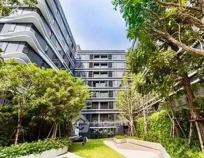 Modern residential building with lush green garden and sleek architectural design.