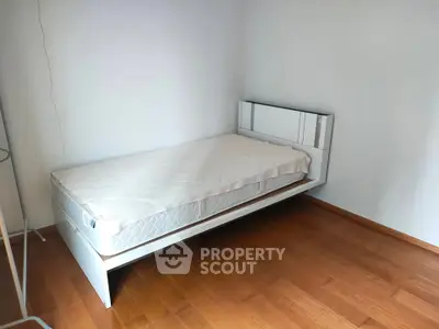Minimalist bedroom with single bed and wooden flooring, perfect for cozy living.