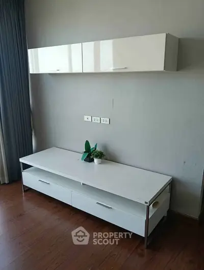 Modern living room with sleek white cabinets and wooden flooring
