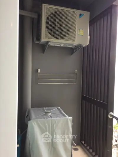 Compact balcony with air conditioning unit and washing machine, ideal for urban living.