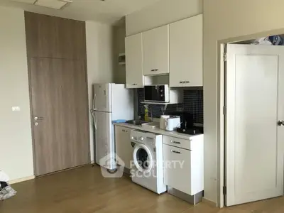 Modern compact kitchen with washing machine and microwave in stylish apartment.