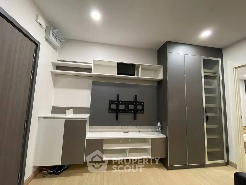 Modern living room with built-in storage and TV mount, featuring sleek design and ample shelving.