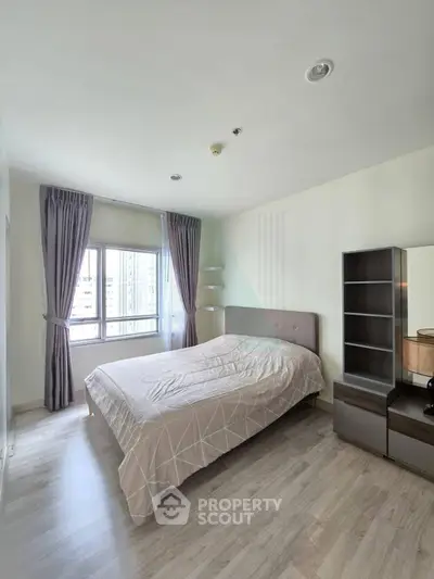 Spacious bedroom with modern decor and large window offering city views.