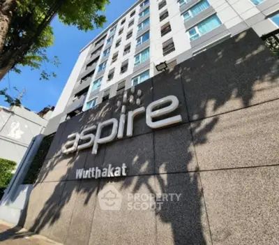 Modern high-rise building exterior with Aspire Wutthakat signage, showcasing urban living.