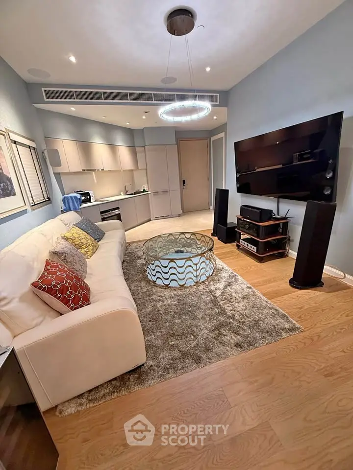 Modern living room with stylish decor, large TV, and open kitchen layout in a cozy apartment.