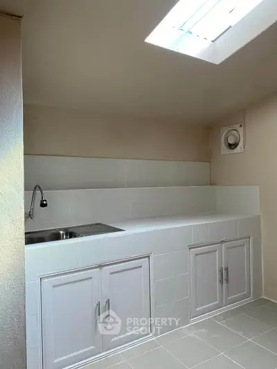 Compact kitchen with skylight and white cabinetry, perfect for efficient cooking in a cozy space.