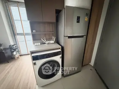 Modern kitchen corner with washing machine and stainless steel fridge in stylish apartment.