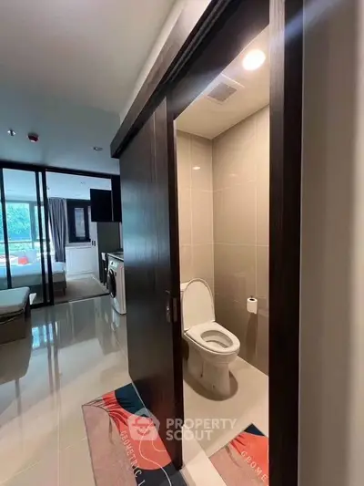 Modern apartment interior featuring a compact bathroom with sliding door and adjacent laundry area.