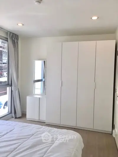 Bright bedroom with large wardrobe and window view in modern apartment