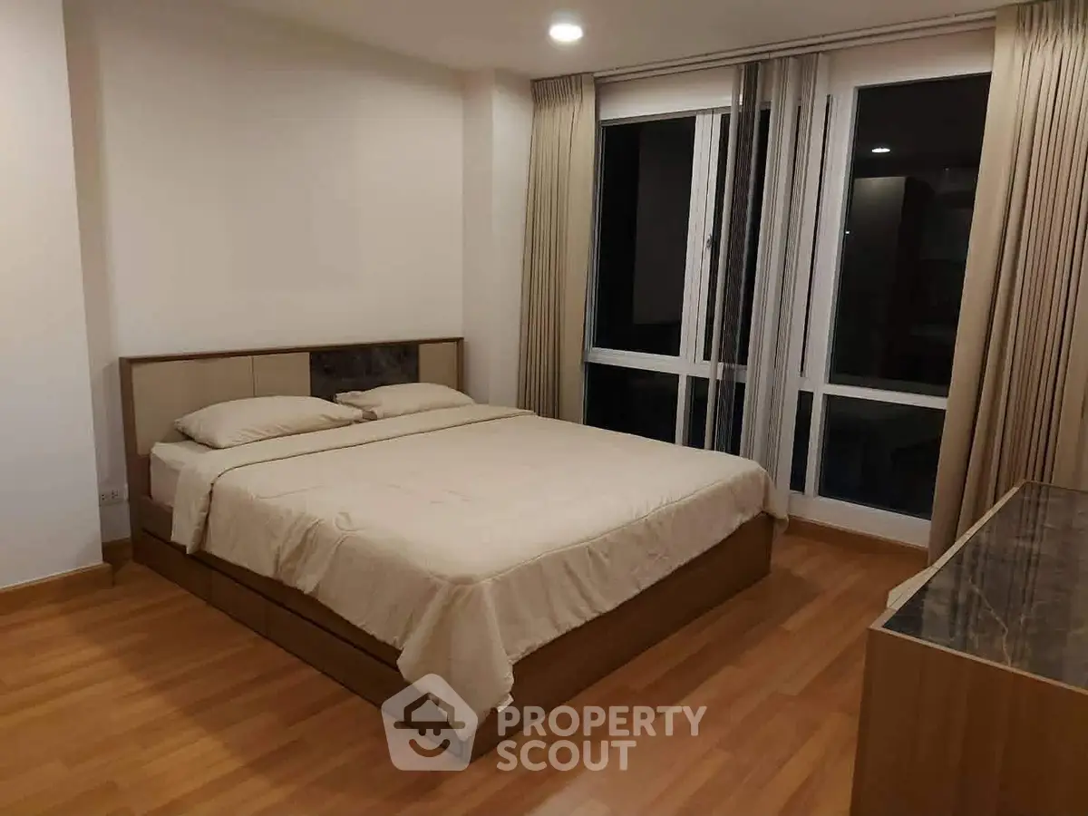 Spacious bedroom with large windows and modern decor in a stylish apartment.