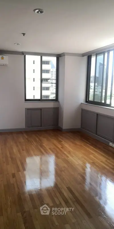 Spacious corner unit with hardwood floors and large windows offering city views.
