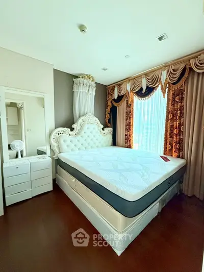 Luxurious bedroom with elegant drapery and ornate headboard in a bright, spacious setting.