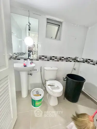 Compact bathroom with modern fixtures and tiled walls, featuring a pedestal sink and toilet.