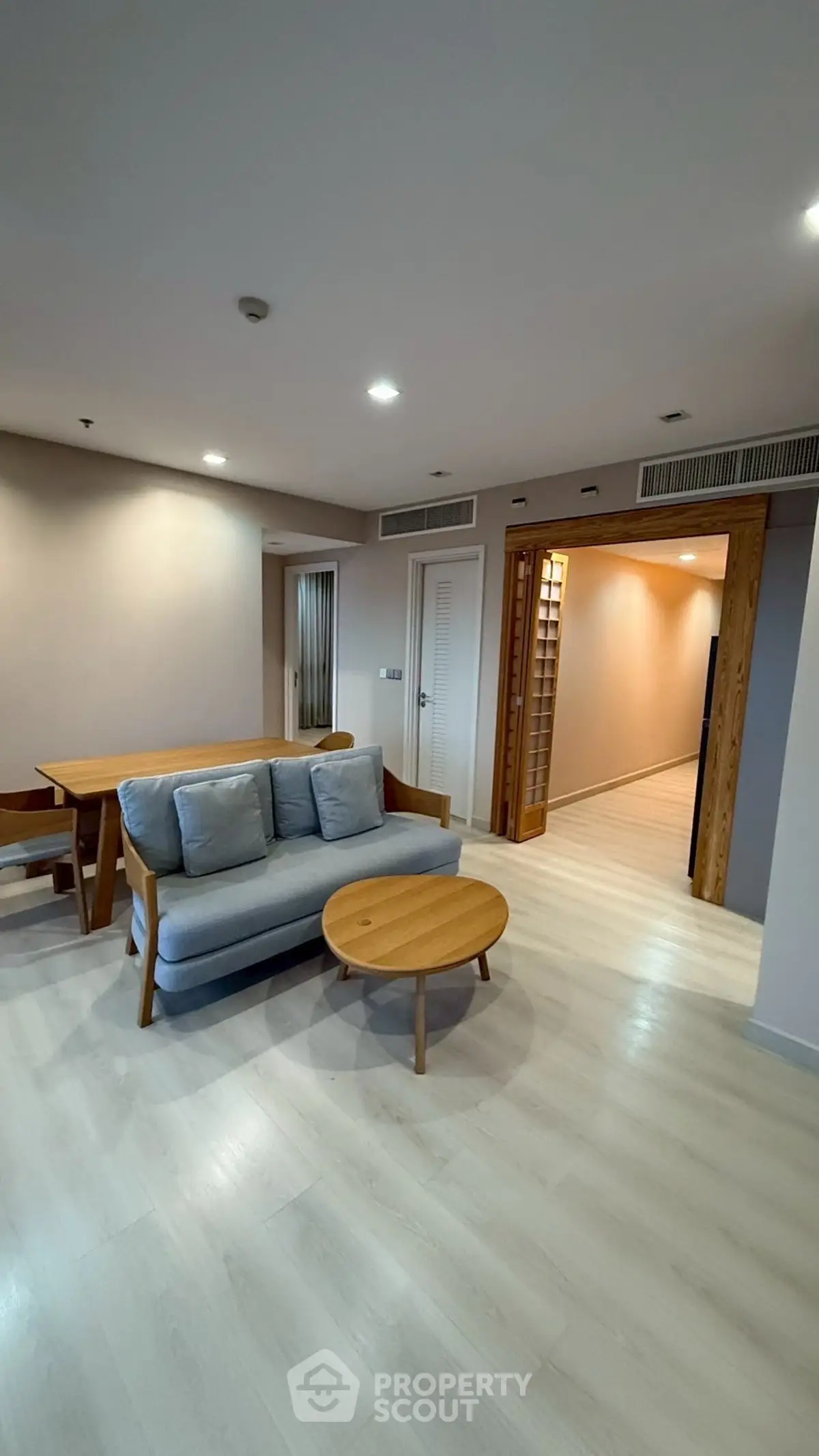 Spacious living room with modern furniture and wooden accents in a stylish apartment.