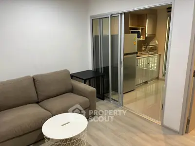 Modern living room with sliding glass doors leading to a sleek kitchen area.