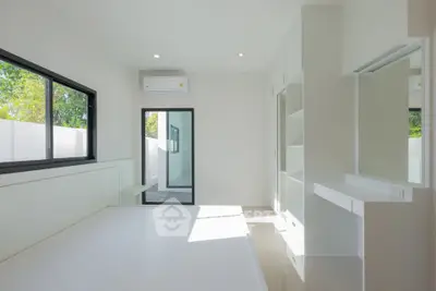 Bright minimalist bedroom with large windows and modern air conditioning unit