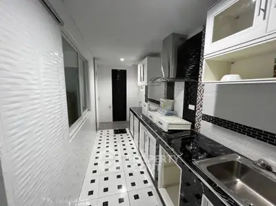 Modern kitchen with sleek black and white design, featuring open shelving and stainless steel appliances.