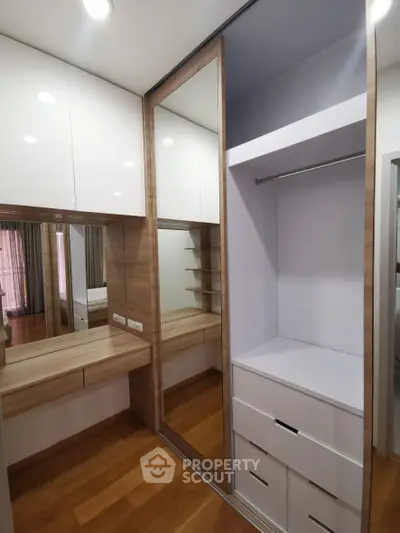 Modern walk-in closet with wooden flooring and built-in storage solutions