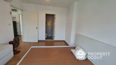 Minimalist bedroom with wooden flooring and attached bathroom in modern apartment.