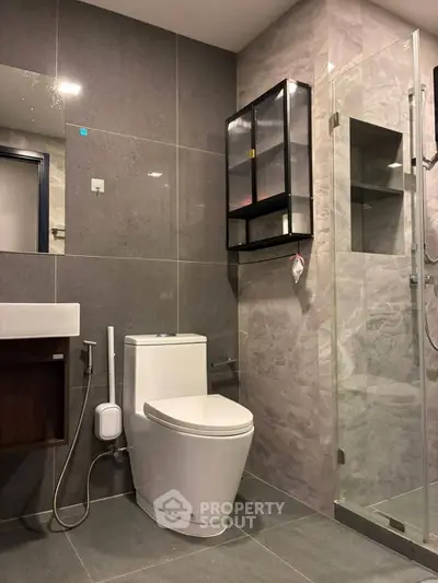 Modern bathroom with sleek design, featuring a glass shower enclosure and contemporary fixtures.