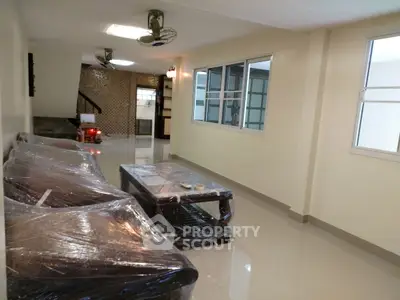 Spacious living room with modern furniture wrapped for protection, large windows, and glossy tiled floor.