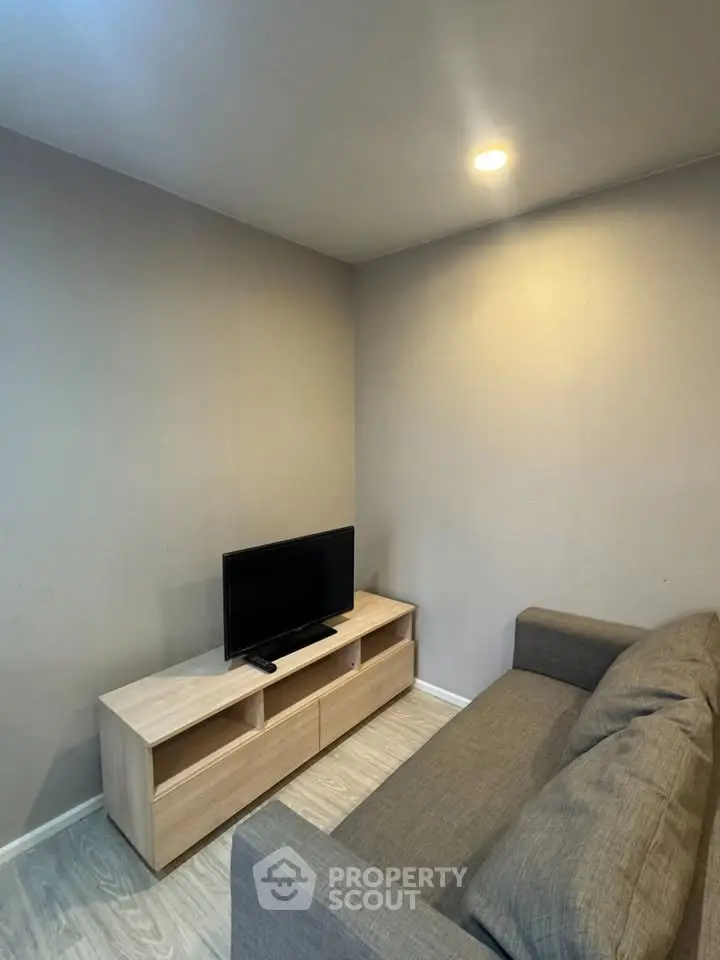 Cozy living room with modern sofa and flat-screen TV, perfect for relaxation.