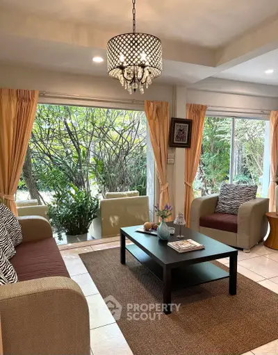 Charming living room with garden view, elegant chandelier, and cozy seating area.